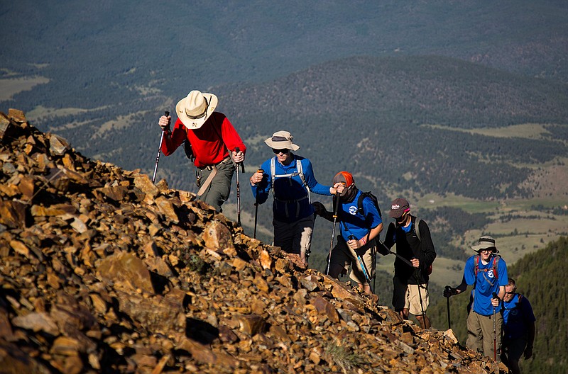 In this July 18, 2017, photo provided by the Philmont Scout Ranch, a crew hikes up Baldy Mountain, the tallest peak on the ranch near Cimarron, New Mexico. Philmont is rebuilding following a devastating wildfire that burned nearly 44 square miles in 2018. Backcountry trails were wiped out along with trail camps. (Hunter Long/Philmont Scout Ranch via AP)