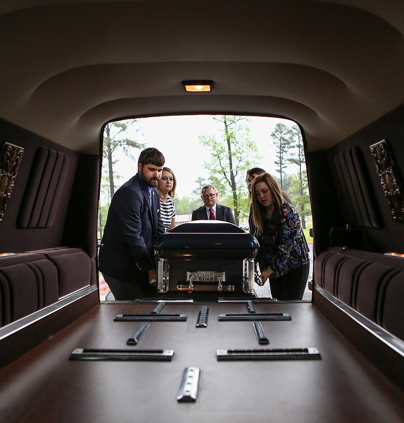 University of Arkansas at Hope-Texarkana students practice moving a casket into a hearse Thursday at the entrance of Hempstead Hall in Hope. The university was recently given a hearse to use for practice and funerals for their funeral service program.