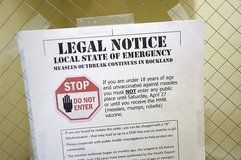 FILE - This March 27, 2019 file photo shows a sign explaining the local state of emergency because of a measles outbreak at the Rockland County Health Department in Pomona, N.Y. Outbreaks in New York state continue to drive up U.S. measles cases, which remain on pace to set a record for most illnesses in 25 years. (AP Photo/Seth Wenig, File)