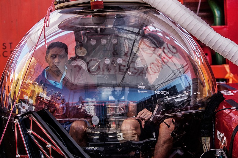 In this Saturday, April 13, 2019, photo, Seychelles President Danny Faure, left, sits inside a submersible on the deck of vessel Ocean Zephyr, off the coast of Desroches, in the outer islands of Seychelles. Faure toured the vessel and was presented with some of the findings and observations made by a British-led science expedition documenting changes taking place beneath the waves that could affect billions of people in the surrounding region over the coming decades. (AP Photo/Steve Barker)