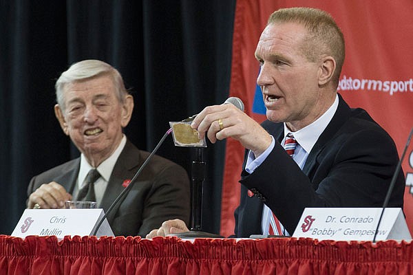 In this April 1, 2015, file photo, retired NBA basketball All-Star and St. John's alumnus Chris Mullin holds a card given to him by his former coach Lou Carnesecca, left, that reads "Peacock today, Feather duster tomorrow" during a news conference to announce his hiring as St. John's men's basketball coach in New York.