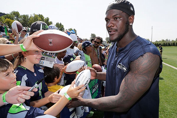 In this Aug. 6, 2018, file photo, Seahawks defensive end Frank Clark signs autographs following training camp in Renton, Wash.