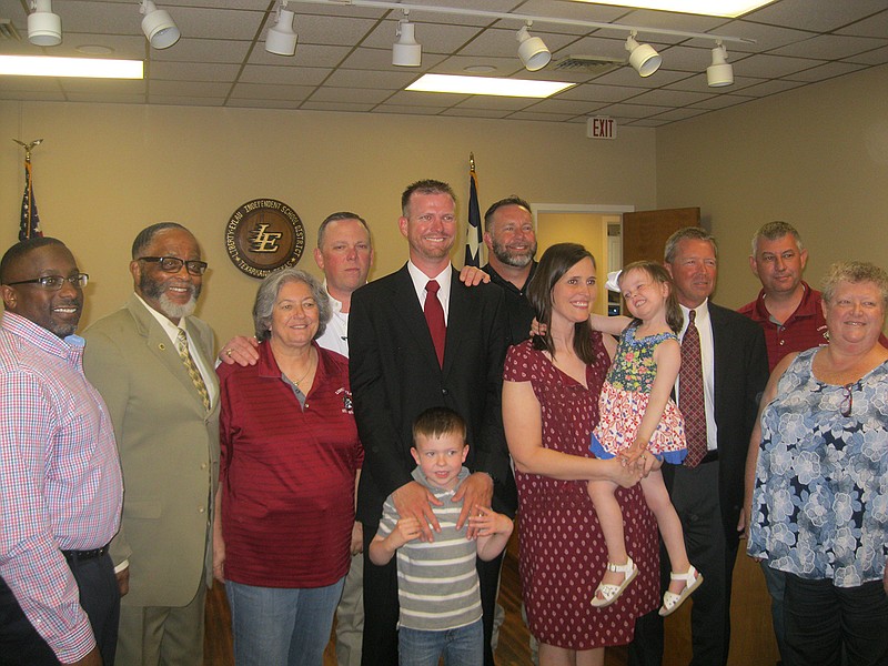 Klint King, center in red tie, poses with his family and members of the Liberty-Eylau ISD Board of Trustees on Thursday after being introduced as the district's new athletic director. King comes to L-E from Richland High School in North Richland Hills, Texas, where he was head track coach, football defensive coordinator and an economics teacher.