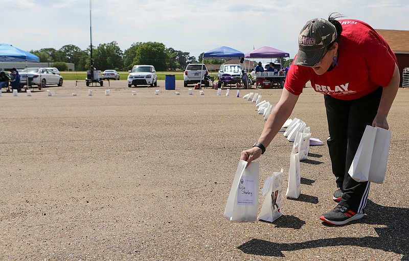 Lisa Barr sets out luminarias that honor those who have survived cancer and those who have died at the Relay for Life event Saturday at the Four States Fairgrounds in Texarkana, Ark.
