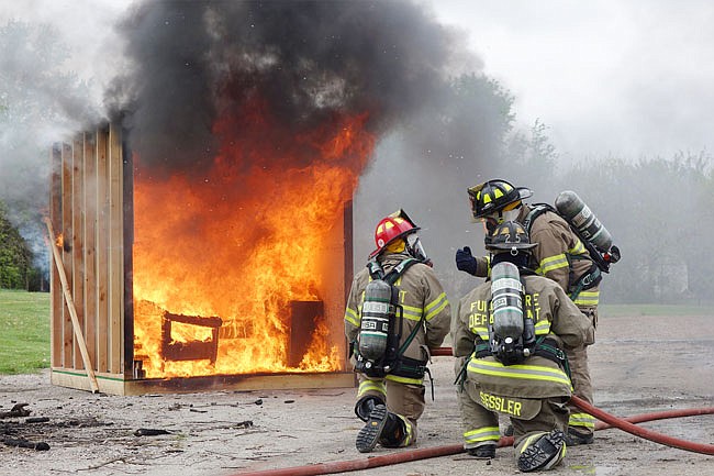 Fulton High School student Evan Gray, FHS activities director Ryan Waters and firefighter Justin Putnam prepare to put out a simulated dorm room fire. The demonstration showed just how quickly a fire can spread.