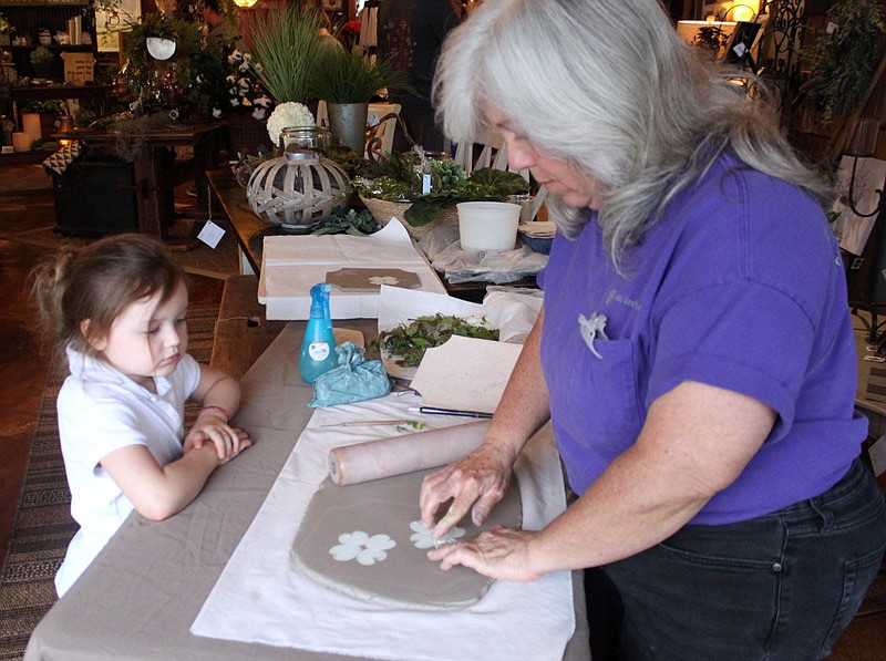 Ann Grotjan, shows Chandler McGill, 4, how to make decorative stoneware pottery April 25, 2019, in Winding Road Gifts and Interiors during An Evening Out on Oak Street in California. 