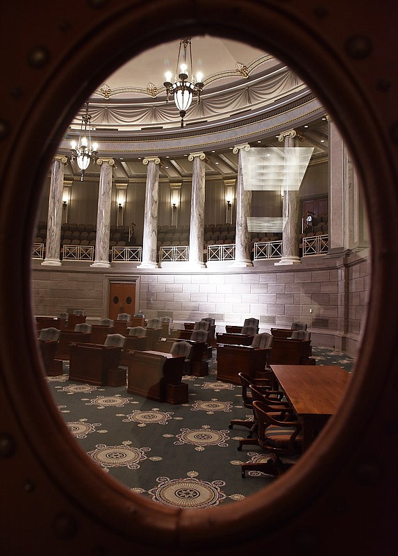 In this January 2018 file photo, a single shaft of sunlight hits the marble wall behind the desks of the Missouri Senate chamber as it stands empty.
