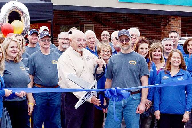 Owner Bob Scruggs cuts the ribbon Wednesday while surrounded by employees and chamber ambassadors during the Scruggs Lumber 100-year anniversary at the Scruggs Lumber Do It center. Having been founded in 1919, Scruggs is one of Missouri's oldest family-owned and operated businesses. 