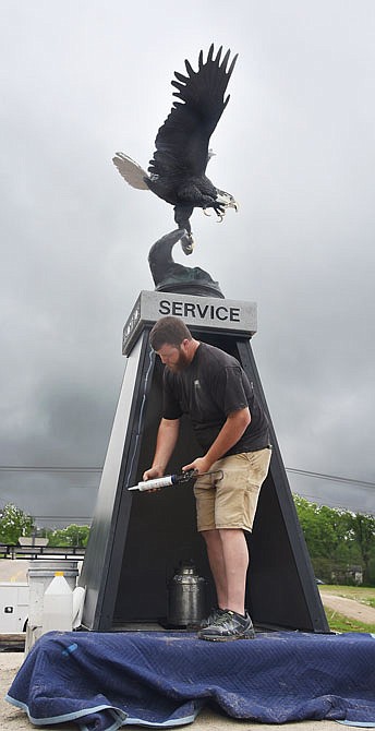 After Hank Stratman placed the time capsule, in the form of an antique metal milk container, inside the framework, Bill Price applied a bead of silicone caulk before he and co-worker Michael Jaegers attached the last slab of black granite to the tower. The pair are from Carved in Stone and are part of the group responsible for helping to bring to life the patriotic roundabout vision of Stratman and the East Side Business Association. 