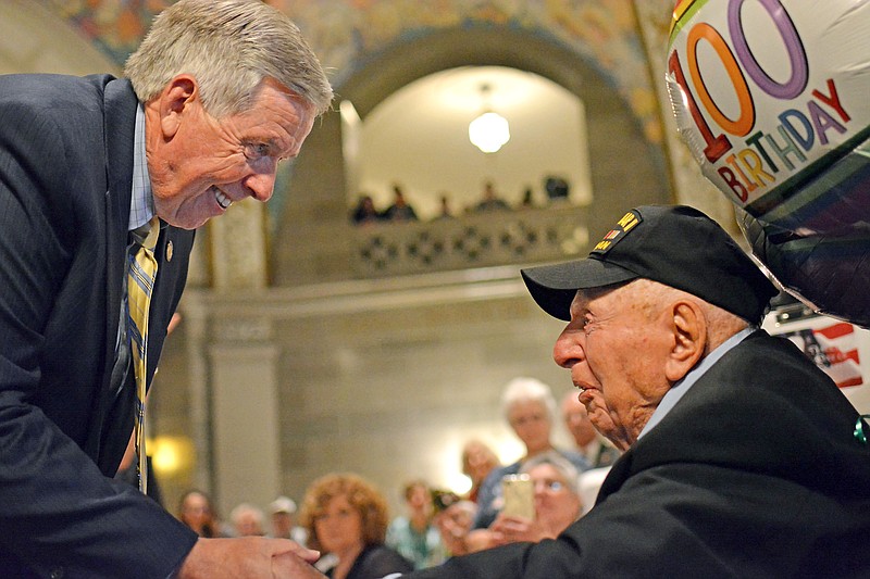 Missouri Gov. Mike Parson shakes hands with WWII veteran Sidney Walton Thursday May 2, 2019 as Walton was recognized for his service during the 68th observance of the National Day of Prayer at the Capitol rotunda. Walton has been traveling across the U.S. with his family for the last year to visit all 50 state capitols. Missouri is his 21st visit. 