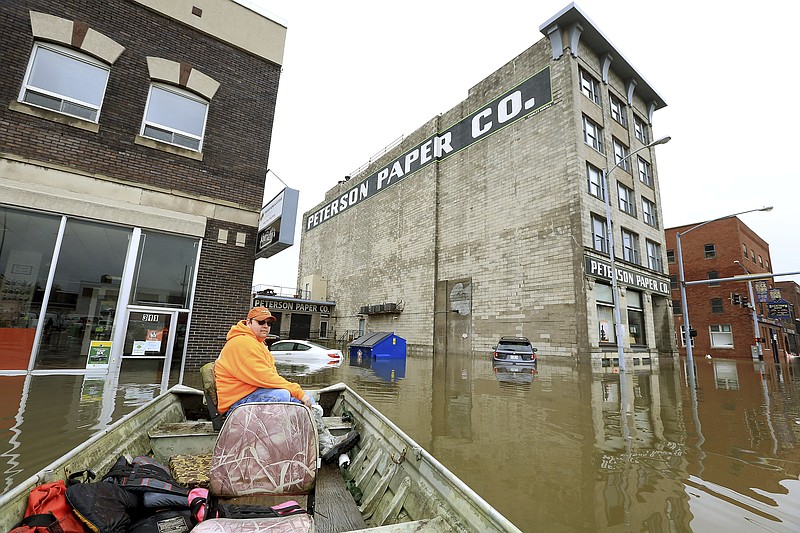 Ryan Lincoln maneuvers his boat through flood water at the intersection of Pershing Ave and E 2nd St. Thursday, May 2, 2019. Lincoln's employer Hahn Ready Mix allowed him to take time off from work to volunteer ferrying people back and forth to their apartments and businesses affected by the flooding in downtown Davenport. The Mississippi River is expected to reach a record level of 22.7 feet Thursday night. (Kevin E. Schmidt/Quad City Times via AP)