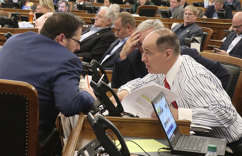 In this Saturday, May 4, 2019, photo Kansas House Taxation Committee Chairman Steven Johnson, right, R-Assaria, confers with House Speaker Ron Ryckman Jr., R-Olathe, ahead of a debate over a Republican income tax relief bill at the Statehouse in Topeka, Kan. The tax bill is designed to prevent individuals and businesses from paying more in taxes to the state because of changes in federal tax laws. (AP Photo/John Hanna)