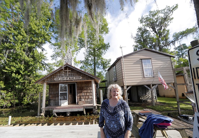 Pat Hymel stands on the dock in front of Our Lady of Blind River Chapel, along Blind River in St. James Parish, La., Tuesday, April 9, 2019. The chapel was built decades ago by her parents, Martha Deroche and her husband Bobby, after Martha had a vision of Jesus kneeling by a rock. Over the years, people have stopped by in boats or kayaks to pray in the one-room chapel. But floods over the years have damaged the little church, and the couple's grandson Lance Weber had to close it about two years ago out of safety concerns. (AP Photo/Gerald Herbert)
