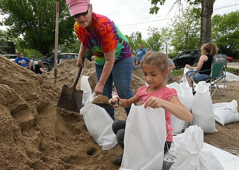 Barbara Moore, left, and her granddaughter Amaya Ward, 7, fill sandbags with other volunteers at the Cherokee Lakes Campground in O'Fallon, Mo., Tuesday, May 7, 2019. The levee at the campground began leaking around 3 a.m. and the owners of the campground put out a call to friends and volunteers to come help fill sandbags to shore up the levee to keep it from failing. (David Carson/St. Louis Post-Dispatch via AP)