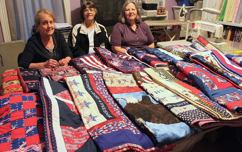 Nineteen quilts wait for delivery to Columbia for veterans who will make the Honor Flight to Washington, D.C. Three local quilters, shown from left, Pam Buda, Linda Bardwell and Brenda Cram, stitched together each of the donated quilts. Glenda Hamilton was not present for the photo.