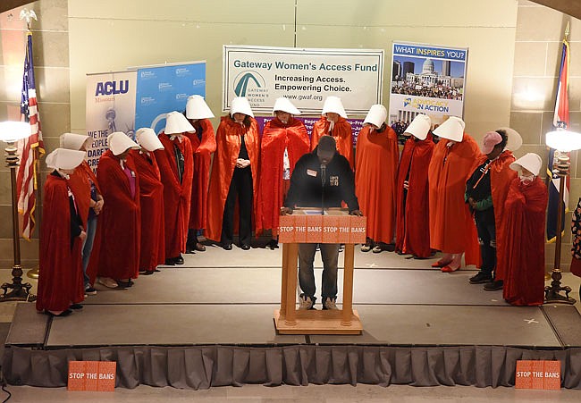 Surrounded by cape-and-hat-wearing women, inspired by "The Handmaid's Tale," Elder Stanley Jackson recites the opening prayer Wednesday as Planned Parenthood was joined by several other organizations for a rally intended to #StopTheBan, which refers to legislation termed the "heartbeat bill." HB126 would ban abortions when the heartbeat of an unborn child can be detected.