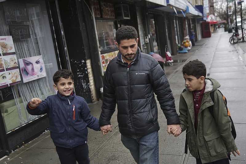 In this March 21, 2019, photo, Sadek Ahmed walks with his sons Adel, 9, right, and Mutaz, 7, after picking them up from school in the Brooklyn borough of New York. Their mother, Amena Abdulkarem, is stuck in Yemen with her two younger sons, the boys’ brothers. Their family’s situation is representative of the toll that the Trump administration’s almost-forgotten travel ban has taken on an untold number of families. (AP Photo/Seth Wenig)