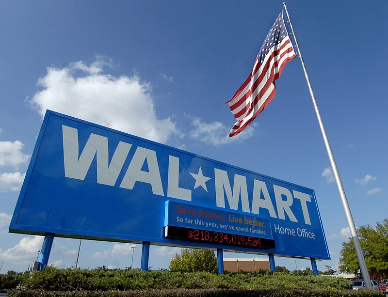 FILE - In this Oct. 5, 2007, file photo, an American flag flies in front of the Walmart Stores Inc. headquarters in Bentonville, Ark. Walmart said Wednesday, May 8, 2019, that it will raise the minimum age for tobacco products and e-cigarettes to 21 in an effort to combat tobacco sales to minors. The world’s largest retailer says the new rule will take effect in July, and will also include its Sam’s Club warehouse stores. (AP Photo/April L. Brown, File)