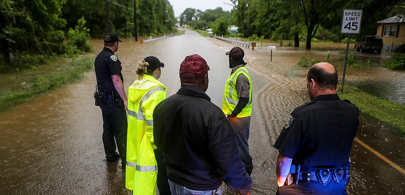Members of the Atlanta Police and Public Works departments discuss where to set up blockades to keep vehicles from driving through the flooded area Wednesday on South William Street in Atlanta, Texas. Heavy thunderstorms brought large amounts of rain that caused flash floods throughout Northeast Texas. Several roads had to be blocked as a precaution.