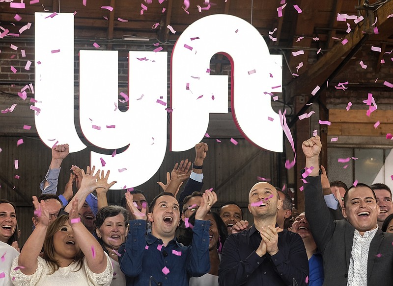 FILE - In this Friday, March 29, 2019 file photo, Lyft co-founders John Zimmer, front second from left, and Logan Green, front second from right, cheer as they as they ring a ceremonial opening bell in Los Angeles, to mark trading on the Nasdaq exchange under the ticker symbol "LYFT." A fare war between Uber and Lyft has led to billions of dollars in losses for both ride-hailing companies as they fight for passengers and drivers. But in one way it has been good for investors who snatched up the newly public companies' stock: The losses have scared off the competition, giving the leaders a duopoly in almost every American city. (AP Photo/Ringo H.W. Chiu)