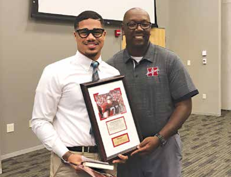 Donning a mock pair of black square-framed glasses similar to those worn by University of Arkansas Razorback football All-American Brandon Burlsworth, Hope High School linebacker Christopher Haywood, left, accepts the Brandon Burlsworth Character Award from Co-Athletic
Director/Head Football Coach Phillip Turner.