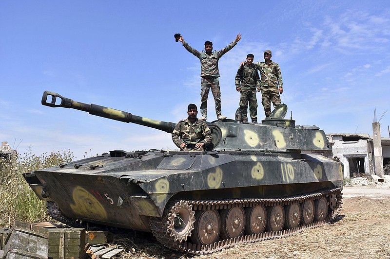 In this photo released by the Syrian official news agency SANA, Syrian army soldiers flash the victory sign as they stand on their tank in the village of Kfar Nabuda, in the countryside of the Hama province on Saturday, May 11, 2019. The Britain-based Syrian Observatory for Human Rights said government forces are now in control of nine villages forming an L shape at the far southern corner of the rebel stronghold. The villages include the strategic village of Kfar Nabuda and the elevated Qalaat Madiq, giving the government troops an advantage over the insurgents. (SANA via AP)