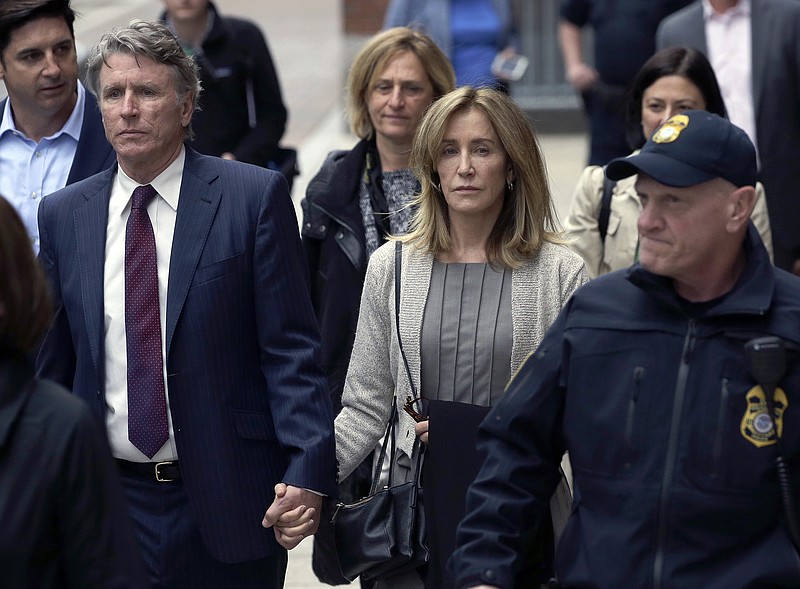 Felicity Huffman, center, departs federal court with her brother Moore Huffman Jr., left, Monday, May 13, 2019, in Boston, where she pleaded guilty to charges in a nationwide college admissions bribery scandal. (AP Photo/Steven Senne)