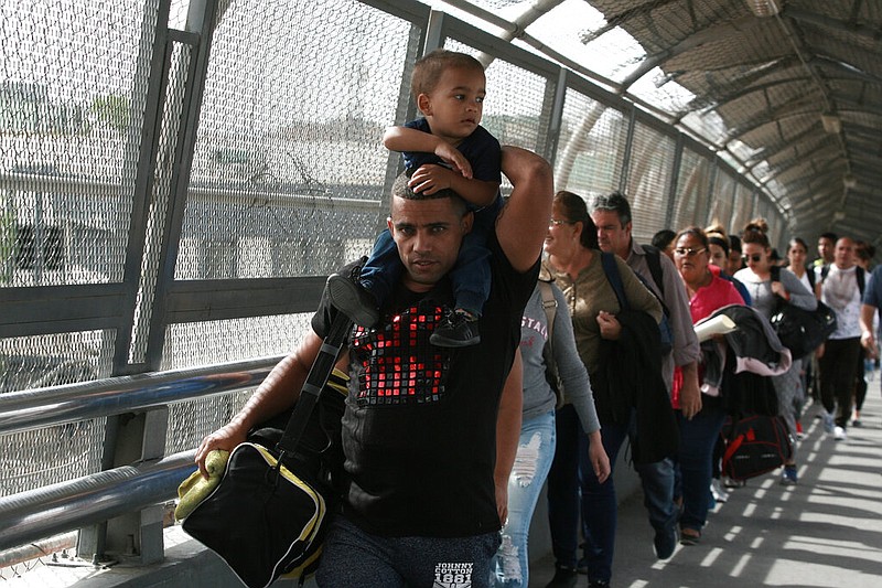 In this April 29, 2019, photo, Cuban migrants are escorted by Mexican immigration officials in Ciudad Juarez, Mexico, as they cross the Paso del Norte International bridge to be processed as asylum seekers on the U.S. side of the border. Burgeoning numbers of Cubans are trying to get into the U.S. by way of the Mexican border, creating a big backlog of people waiting on the Mexican side for months for their chance to apply for asylum.