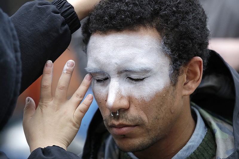 FILE - In this Oct. 31, 2018, file photo, a man, who declined to be identified, has his face painted to represent efforts to defeat facial recognition during a protest at Amazon headquarters over the company's facial recognition system, "Rekognition," in Seattle. San Francisco is on track to become the first U.S. city to ban the use of facial recognition by police and other city agencies as the technology creeps increasingly into daily life. Studies have shown error rates in facial-analysis systems built by Amazon, IBM and Microsoft were far higher for darker-skinned women than lighter-skinned men. (AP Photo/Elaine Thompson, File)