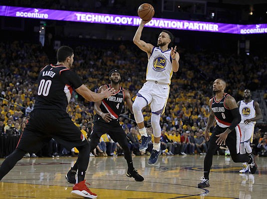 Stephen Curry of the Warriors shoots between Trail Blazers teammates Maurice Harkless (4), Enes Kanter (00) and Damian Lillard during the first half of Tuesday night's Game 1 of the Western Conference finals in Oakland, Calif.