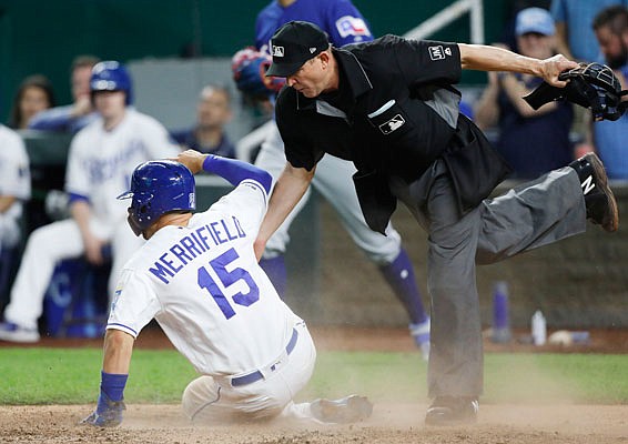 Home plate umpire Jeff Kellogg avoids Whit Merrifield of the Royals as he scores a run during the seventh inning of Tuesday night's game against the Rangers at Kauffman Stadium.