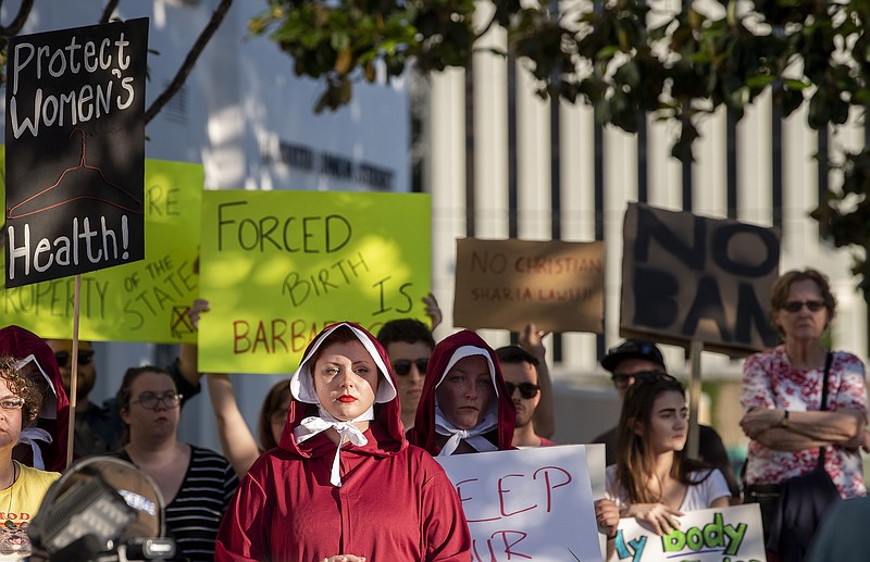 Margeaux Hartline, dressed as a handmaid, protests against a ban on nearly all abortions outside of the Alabama State House in Montgomery, Ala., on Tuesday, May 14, 2019.  (Mickey Welsh/The Montgomery Advertiser via AP)