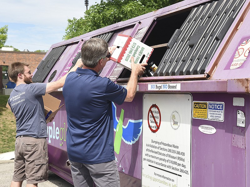 Chris Hillen and David Speradino, right,  toss their glass bottles and jars into the glass collection dumpster on the parking lot of Sav-a-lot Thursday, May 16, 2019. 