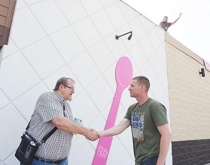 Tom Schultz hands an insulated cup to Robert Goser after Goser made a donation Friday to Special Olympics Missouri. Schultz and Adam Koestner, on the roof waving, both caseworkers at Algoa Reformatory, were at Dunkin Donuts accepting donations for SOMO.