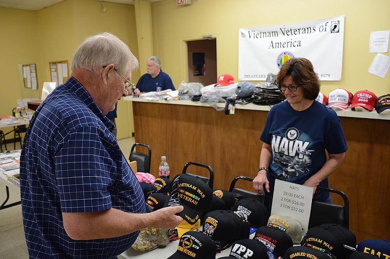 Navy Vietnam veteran James Cook of Texarkana, Ark., looks over ball caps offered by Connie Smith of the Vietnam Veterans of America Chapter 278 at Saturday's Veterans Information Fair in Texarkana, Texas. (Photo by Tom Morrissey)