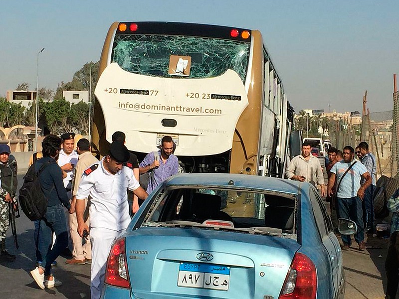 Police inspect a car and a bus that were damaged by a bomb Sunday, May 19, 2019, in Cairo, Egypt. Egyptian officials say a roadside bomb hit the tourist bus near the Giza Pyramids. They said Sunday's blast wounded at least 17 people, including tourists.