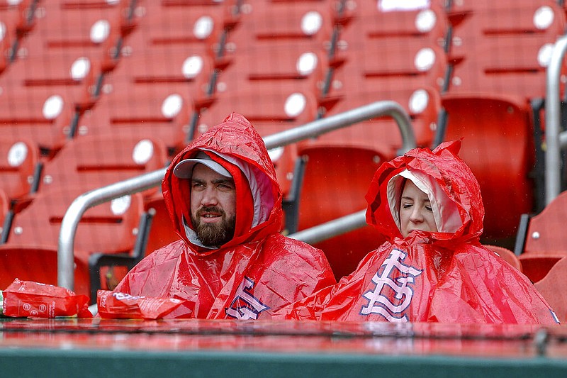Chuck Lane, left, and his wife Elizabeth wait in the rain for the start a baseball game between the St. Louis Cardinals and the Pittsburgh Pirates Saturday, May 11, 2019, in St. Louis. (AP Photo/Scott Kane)