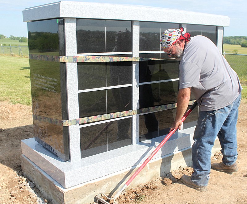 Daniel Caro works to level the ground surrounding the newly-placed granite column-burium at Flag Spring Cemetery. Caro and Tripp Johnson of Johnson Granite Supply placed the structure May 14, 2019, to give Moniteau County residents a permanent place for inurnment.