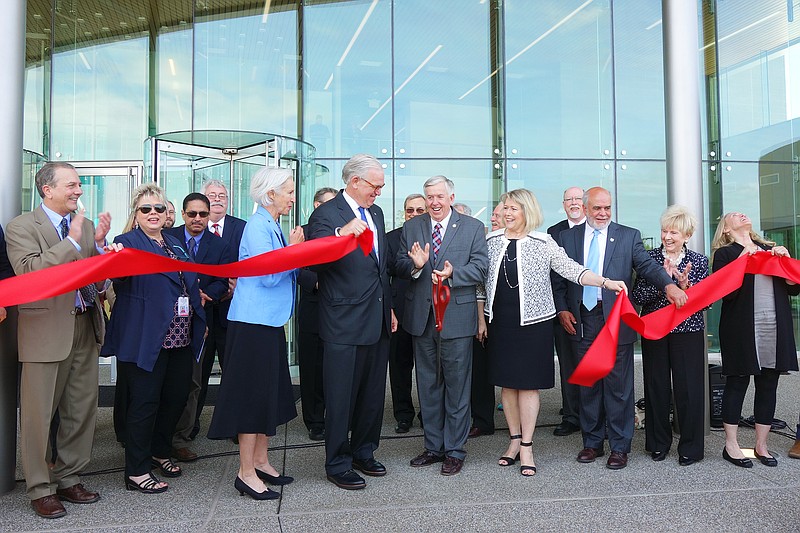 <p>Helen Wilbers/For the News Tribune</p><p>Missouri Gov. Mike Parson, center, flanked by former governor Jay Nixon (left), First Lady Teresa Parson and a bevy of other officials and dignitaries, cuts the ribbon at the Nixon Forensics Center. During his speech, Parson celebrated the chance to provide a high-quality facility for the Fulton State Hospital’s patients and staff.</p>