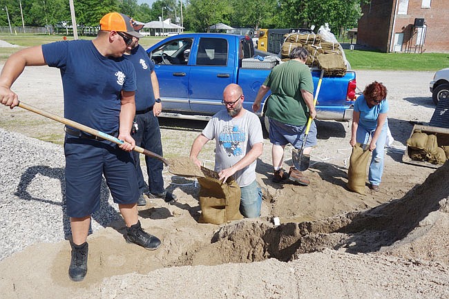 Volunteers including John Putnam, left, Chris Thompson, Kenny Ford, Jim Keyes and Kim Keyes fill sandbags to protect Amvets Post 153. The sacks and the first load of sand were donated by the Missouri Department of Transportation, said Mary Ann Fritz.