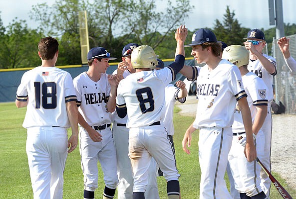 Zach Woehr (8) is congratulated by his Helias teammates after scoring a run Wednesday in a Class 4 sectional game against Marshfield at the American Legion Post 5 Sports Complex.