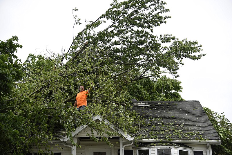 Jenna Kieser/News Tribune
An employee from New Age Renovations removes tree branches and debris off the roof of a home on Dunklin st. on Thursday.