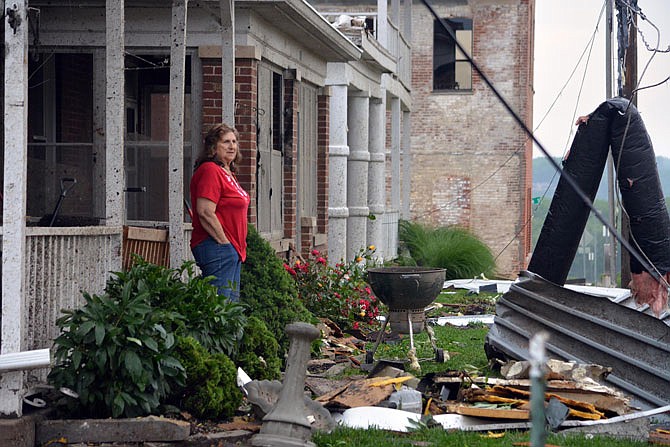 Linda Treacle looks at a large amount of debris while standing on her front porch Thursday on Lafayette Street. Damages wear reported throughout the city stretching from Ellis Boulevard and across the Missouri River.