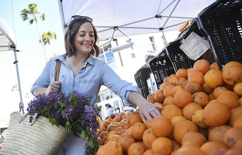 This April 10, 2019 photo shows Gaby Dalkin shopping for oranges at Santa Monica Downtown Farmers Market in Santa Monica, Calif. Dalkin, the chef behind the popular Website and social media accounts, "What’s Gaby Cooking," is forging her own path. Every Monday she posts a live demo to Instagram as she cooks dinner which has become appointment viewing for some fans. Her husband films it and reads questions from viewers as she’s cooking. (AP Photo/Chris Pizzello)