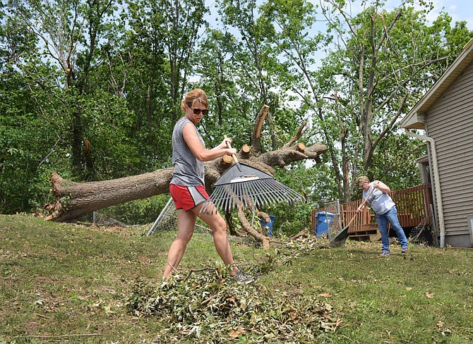 Blair Oaks teachers Danette Bax, front, and Dana Fitzpatrick rake debris Friday near a home on Holiday Road. The pair decided they could help the homeowner, who also teaches in Blair Oaks, after learning about damages from Wednesday's tornado.