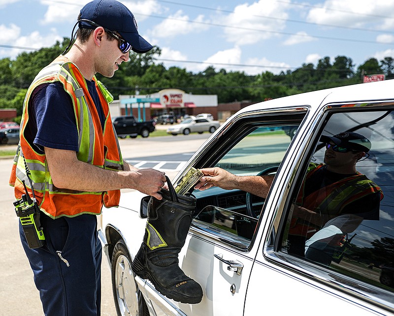 Texarkana, Ark., firefighter Dillon Foreback lets a person put money into a boot Friday at Arkansas Boulevard and Jefferson Avenue in Texarkana, Ark. Friday was the starting day for the Fill the Boot Drive for the Arkansas-side Fire Department. The drive is to collect donations for the Muscular Dystrophy Association that will help with research, MDA Care Clinics, camps for children and other purposes. The Fire Department will be at the intersection from 2 p.m. to 6 p.m. today and Sunday.