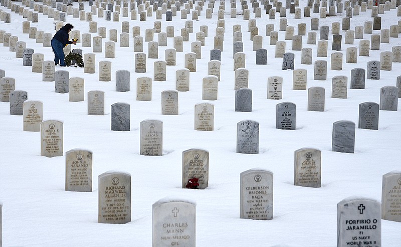 A woman places flowers on the grave of a loved one at the Santa Fe National Cemetery in Santa Fe, New Mexico, which is administered by the United States Department of Veterans Affairs. (Photo by Robert Alexander/Getty Images)