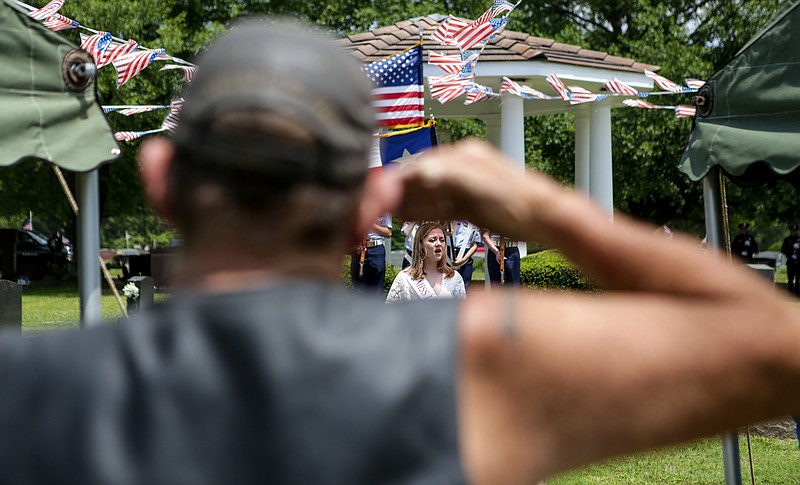 David Tiner salutes the American Flag while Allie Groves sings the National Anthem at the Memorial Day service at Hillcrest Memorial Park on Monday, May 27, 2019, in Texarkana, Texas.