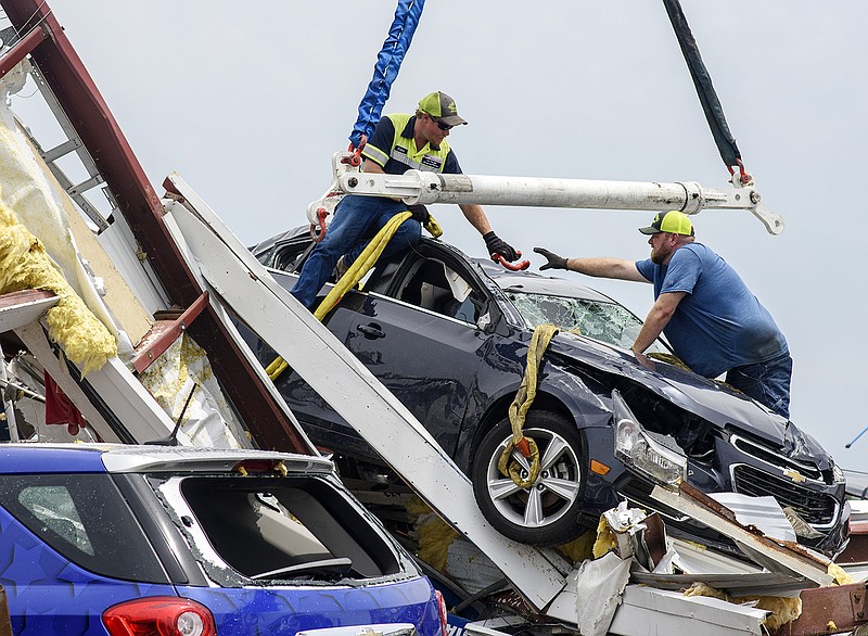 Tow Pro operators Cory Burton, left, and Michael Hutchison prepare to lift a damaged vehicle Monday afternoon, May 27, 2019, out of the wreckage of what was once the Riley Chevrolet Buick GMC service area.