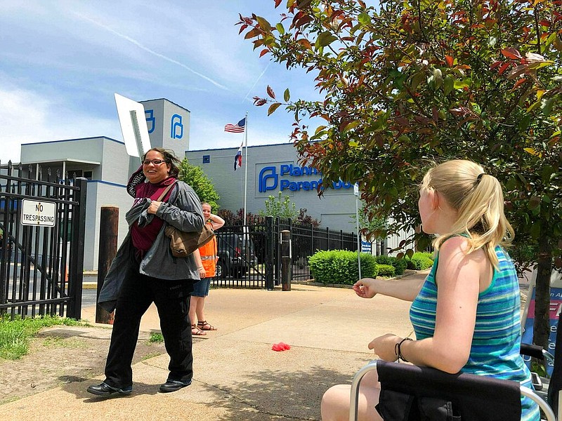 In this May 17, 2019 file photo, Teresa Pettis, right, greets a passerby outside the Planned Parenthood clinic in St. Louis. Pettis was one of a small number of abortion opponents protesting outside the clinic on the day the Missouri Legislature passed a sweeping measure banning abortions at eight weeks of pregnancy. Planned Parenthood says Missouri's only abortion clinic could be closed by the end of the week because the state is threatening to not renew its license, which expires Friday, May 31.